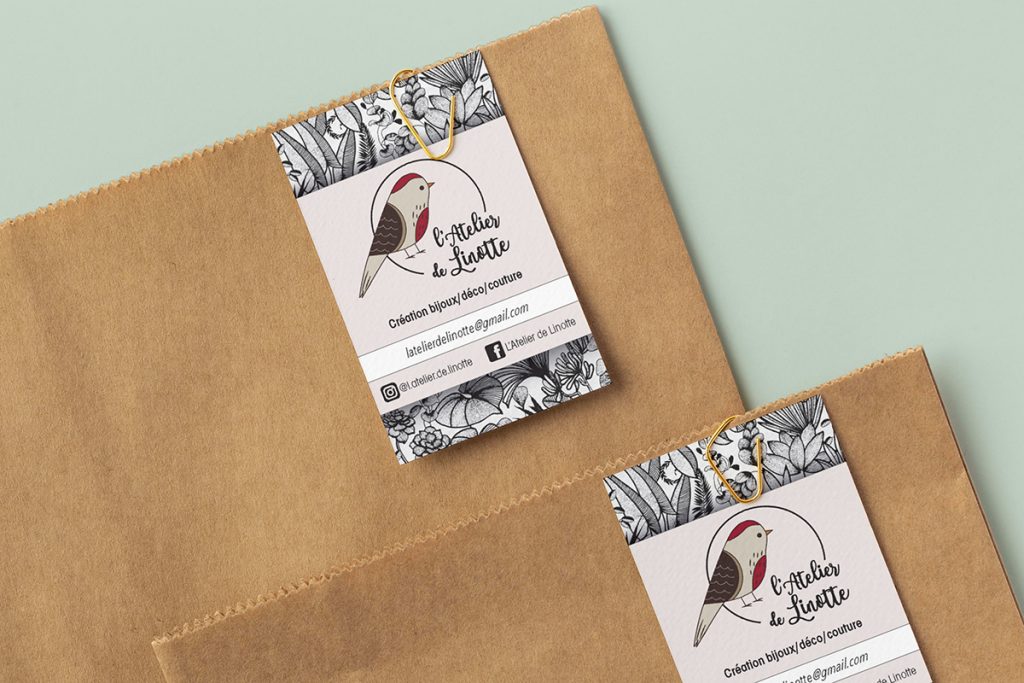 Carte de visite verticale fixée sur un sachet kraft pour l'Atelier de Linotte, création de papeterie et identité visuelle par Well Com Studio Graphique à Albi.