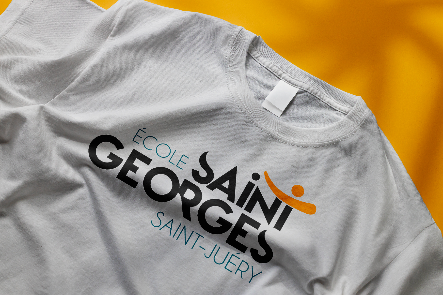 T-shirt gris plié avec impression du logo École Saint-Georges, marquage textile pour établissement scolaire par Well Com Studio Graphique à Albi.