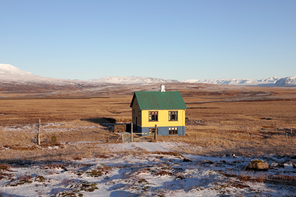 Photographie d'une maison jaune isolée au toit vert dans un paysage enneigé en Islande, photographie de voyage et inspiration couleur par Well Com Studio Graphique à Albi.