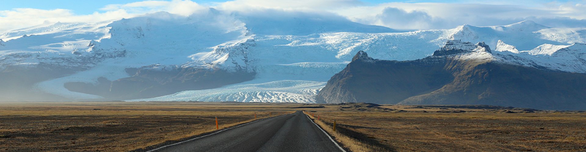 Photographie de paysage d'une route en Islande avec glacier et montagnes enneigées en arrière-plan, prise de vue artistique et composition visuelle par Well Com Studio Graphique à Albi.